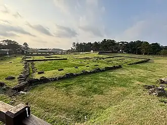 A grassy field with stones lining the ground marking out building outlines