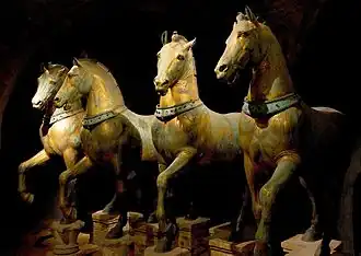 A group of bronze statues of four horses harnessed for chariot driving