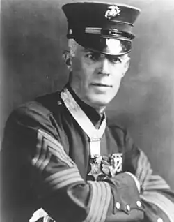 Top half of man in formal 1900s military dress, wearing a star-shaped medal on a ribbon around his neck.