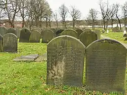 Upright gravestones with many names carved into each stone