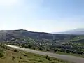 Kovli village in the valley with green hills and a winding road