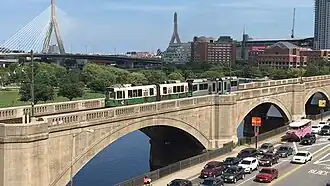 A light rail train on a concrete arch viaduct in an urban area