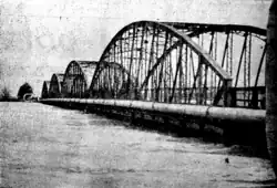 A bridge in water reaching almost up to its roadbed