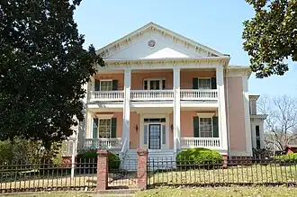 Two-story building fronted with a portico with four Greek columns