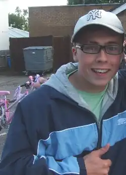 A man with a white hat and glasses, smiling at the camera.