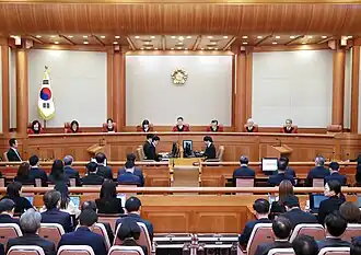 The Constitutional Court chamber. At the center of the bench in the back of the chamber, Moon is speaking.
