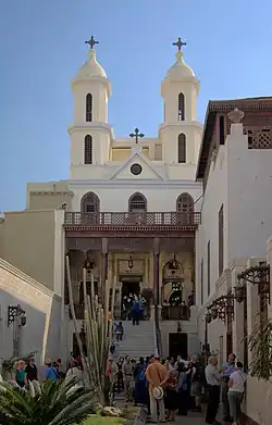 Exterior view of church facade showing twin bell towers with tourists gathered in front