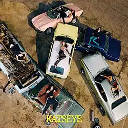 The members of Katseye lying on the tops of cars