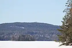 Åmänningen is covered in snow and ice. Landsberget is visible in the background. The picture is taken from Halvarsviken.