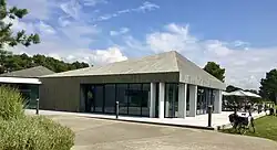 A grey new building, with a golf course in the background