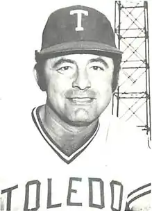 A man wearing a baseball jersey with "TOLEDO" across the cheast and a cap with a "T" insignia