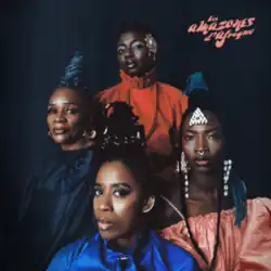 Four Black women with various hairstyles and bright clothes looking towards the camera in front of a dark backdrop
