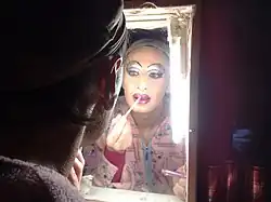 A drag queen putting on lip liner