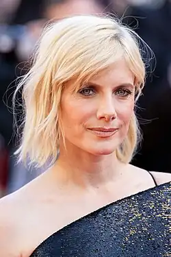 Laurent smiling at the camera in a white shirt.