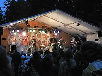 a group of men playing horns, guitars, and percussion in a tent
