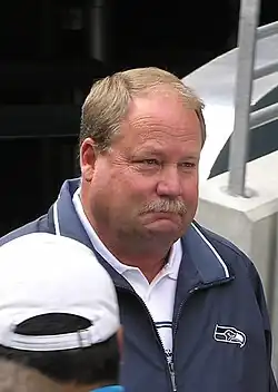 Candid head and shoulders photograph of Holmgren wearing a green jacket over a white shirt