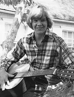Johnny Doran sitting in a tree and playing guitar. Approximately age 15.