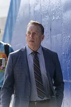 Color photograph of white man wearing a blue suit.