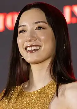 Nagano at press event facing camera with arms at sides