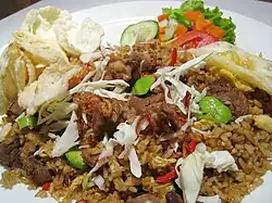 Nasi goreng with various condiments includes; emping cracker, fried shallots, acar pickles and lalab.