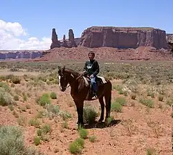 A young Navajo boy on horseback in Monument Valley. The Navajo Nation includes much of the Four Corners area, including the valley, used in many western movies.