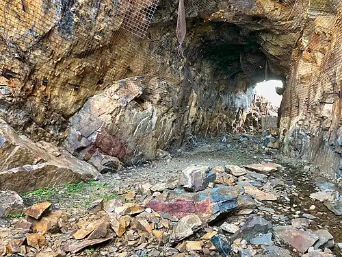 2018 photograph of Needle's Eye Tunnel, near the summit of Rollins Pass. This view shows the northeast portal in the foreground; the southwest portal can be seen in the background. Wire mesh and metal dowels were installed in August 1987 to help reduce additional rock falls and preserve the condition of the tunnel constructed in 1903 (122&nbsp;years ago)&nbsp;(1903).