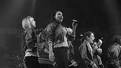 A group of female singers perform live on a stage.