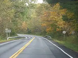 A highway cutting through a forest. Fall foliage is beginning to emerge.