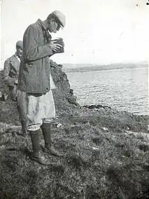 Photograph by R.C. MacLeod showing a man taking a photograph with a hand-held camera.