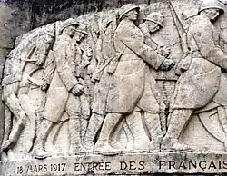 The relief on the Noyon war memorial commemorating the re-entry of the 13th Army Corps on 18 March 1917