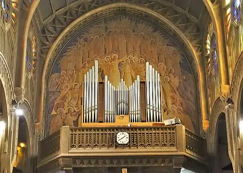 The organ in the tribune of the nave, in front of a painting of a choir of angels