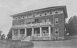 A three-story brick building on a hill.