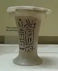 Photograph of a small white vase with black hieroglyphs on it