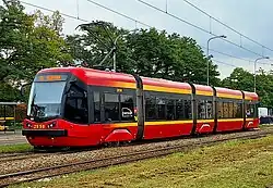 Mostly red tram with yellow stripes above and below the windows