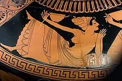 A topless woman, holding a wine-cup, with her hand to her mouth as she shouts to a figure offscreen.