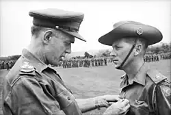 Major Harry Smith of St. John's Wood, Brisbane, Qld, receiving the ribbon to the Military Cross for gallantry from Brigadier O. D. Jackson.