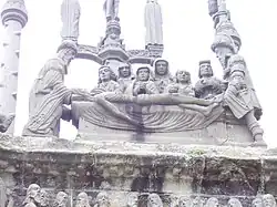 The "Mise au tombeau" on the east face of Pleyben's calvary. In a sombre scene Jesus' body is prepared for burial in the tomb.