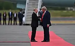 Putin and Trump shaking hands on the red carpet