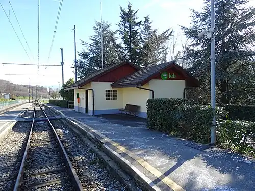 One-story building with gabled roof next to tracks and platforms