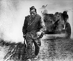 Soldier's work, a soldier walks along the road, behind him artillery raises clouds of dust and pushes a 45 mm anti-tank gun, Russia, August 1, 1943.
