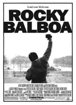The back of Rocky Balboa (Sylvester Stallone) in a hoodie pumping his fist, in front of a view of Benjamin Franklin Parkway.