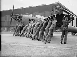 Men pushing an aircraft in a black and white iage
