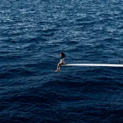 Cover art for "SOS": SZA sitting at the edge of a diving board in the middle of the sea