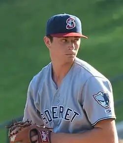 A man in a light baseball uniform and dark cap