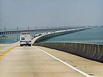 A view of a long bridge over water: a number of cars are visible in the left hand lane