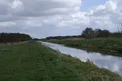 Straight watercourse running between flat grassy fields.