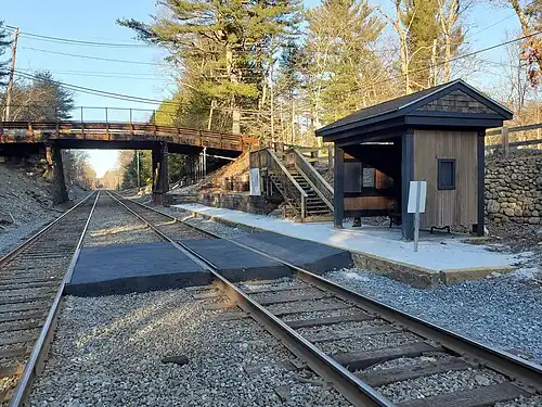 A wooden shelter with a gravel platform next to a double-track railway line