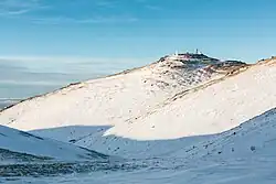 "The site in winter, with snow covering the mountains and the summit region."