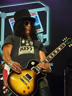 Slash playing an electric guitar and wearing a black top hat.