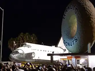 The Randy's Donuts sign alongside Space Shuttle Endeavour as it is ferried through the streets of Los Angeles on Friday, October 12, 2012.